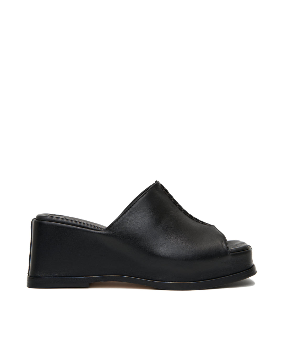 Women's wedge platform mule slide-on shoes made from buttery soft premium European black leather. The shoe design features a wholecut upper, meaning that it's been cut in one continuous piece. The toe and heel of the shoe are a chiseled square shape. The insole is fully padded for all-day comfort and the nubuck sole features non-slip rubber inserts. The perfect 90s inspired cool girl shoe for spring summer and fall.