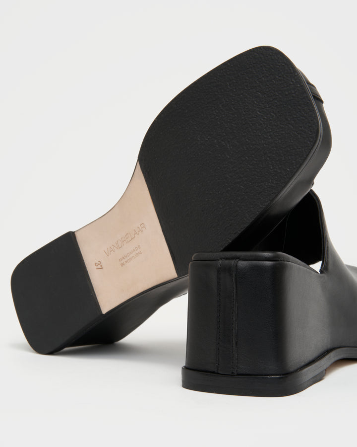 Women's wedge platform mule slide-on shoes made from buttery soft premium European black leather. The shoe design features a wholecut upper, meaning that it's been cut in one continuous piece. The toe and heel of the shoe are a chiseled square shape. The insole is fully padded for all-day comfort and the nubuck sole features non-slip rubber inserts. The perfect 90s inspired cool girl shoe for spring summer and fall.