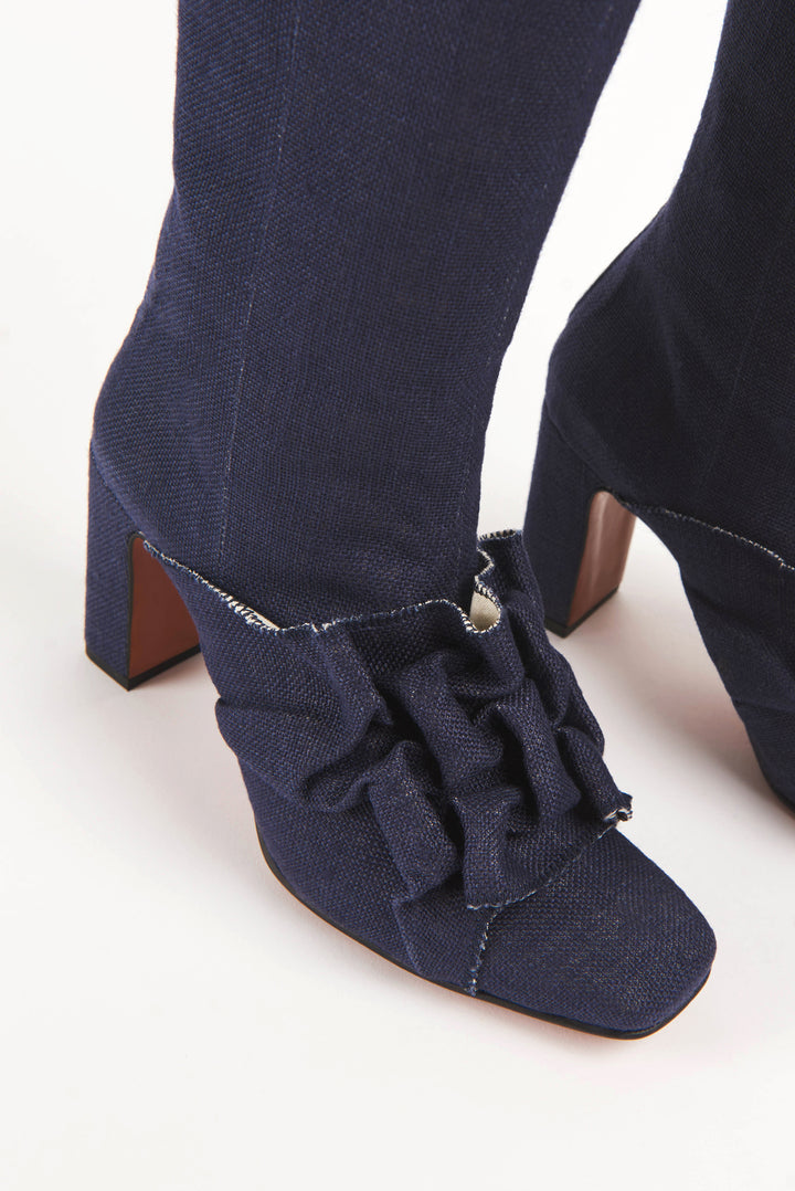 Women's navy blue vegan linen canvas fabric high heel boot with square chiseled toe. Ruffle Canadian smocking detailing on shoe. Sculptural silhouette boot for autumn fall winter season. Mid-calf high heel boots for women with a metal zipper at the back. Luxury shoes and boots made in Portugal.