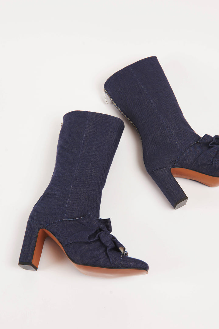 Women's navy blue vegan linen canvas fabric high heel boot with square chiseled toe. Ruffle Canadian smocking detailing on shoe. Sculptural silhouette boot for autumn fall winter season. Mid-calf high heel boots for women with a metal zipper at the back. Luxury shoes and boots made in Portugal.