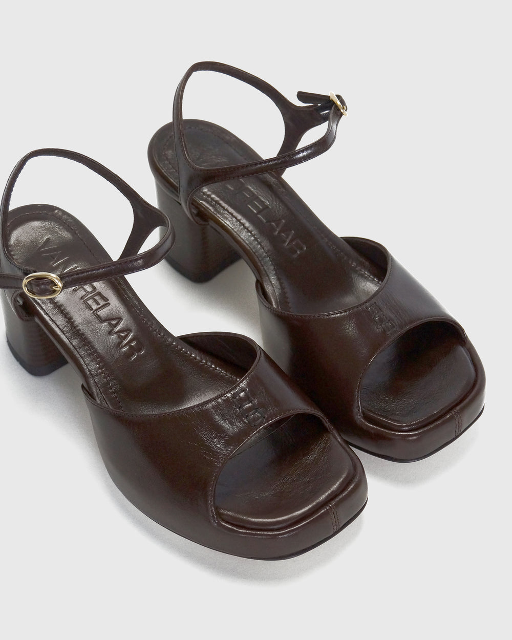 Women's mid-heel block heel open toe sandal with a concealed hidden platform of 2cm (3/4 inch) height and a stacked effect sturdy block heel of 6.5cm (2 3/4 inch) height. The elegant, minimal and timeless sandals comes with a dainty ankle strap that is elasticated to provide additional comfort. The insole is cut to a square toe shape and is fully padded for ultimate all-day comfort. This is the perfect 90's inspired cool girl sandal to wear all spring summer! Made from premium shiny espresso brown leather.