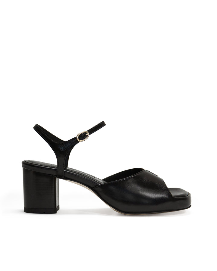 Women's mid-heel block heel open toe sandal with a concealed hidden platform of 2cm (3/4 inch) height and a stacked effect sturdy block heel of 6.5cm (2 3/4 inch) height. The elegant, minimal and timeless sandals comes with a dainty ankle strap that is elasticated to provide additional comfort. The insole is cut to a square toe shape and is fully padded for ultimate all-day comfort. This is the perfect 90's inspired cool girl sandal to wear all spring summer! Made from premium shiny black leather.