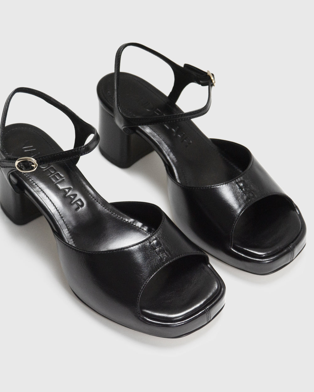 Women's mid-heel block heel open toe sandal with a concealed hidden platform of 2cm (3/4 inch) height and a stacked effect sturdy block heel of 6.5cm (2 3/4 inch) height. The elegant, minimal and timeless sandals comes with a dainty ankle strap that is elasticated to provide additional comfort. The insole is cut to a square toe shape and is fully padded for ultimate all-day comfort. This is the perfect 90's inspired cool girl sandal to wear all spring summer! Made from premium shiny black leather.